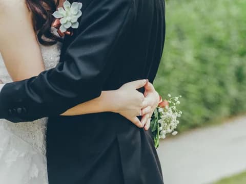 Les mariés enlacés, la mariée tenant son bouquet dans le dos