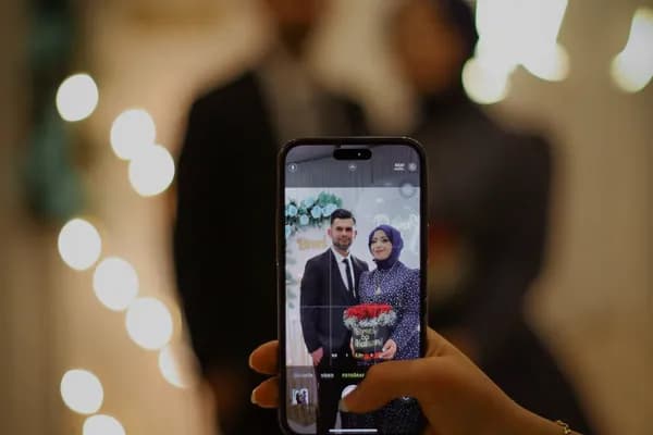 Un invité tient son téléphone ; la photo des mariés vit dans l'écran